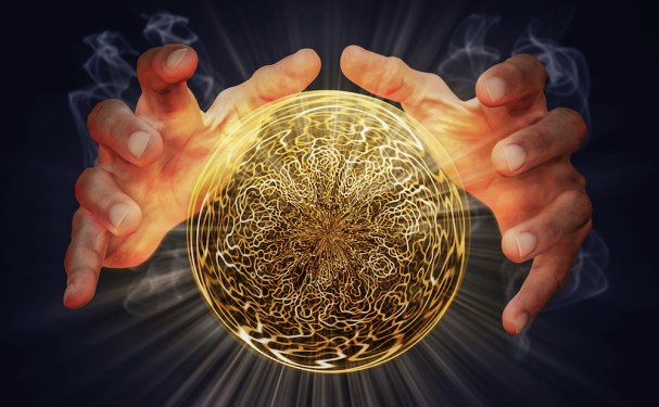 Cropped Image Of Person Holding Illuminated Crystal Ball Against Black Background