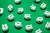 16 small white piggy banks placed randomly on green surface, high angle of view