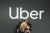 A man stands in front of an Uber logo