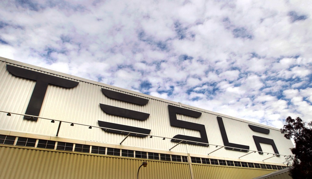 Signage stands outside a Tesla Motors Inc. auto plant.