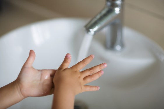 Cropped Image Of Girl Washing Hands By Bathroom Sink