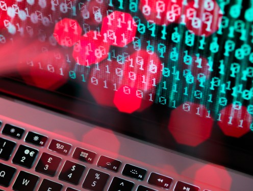 Fibre optic data containing a computer virus hitting a laptop screen.