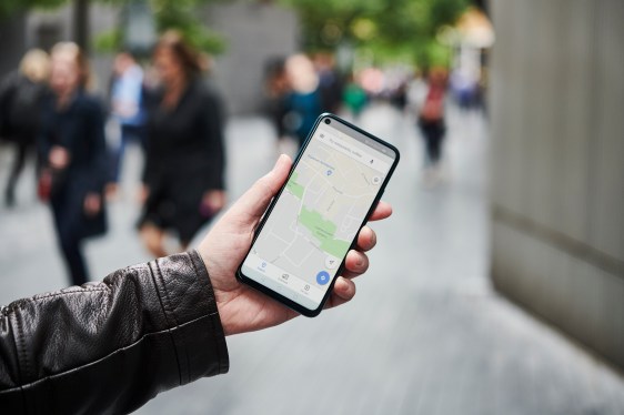 Detail of a man holding up an Honor 20 Pro smartphone with the Google Maps app visible on screen.