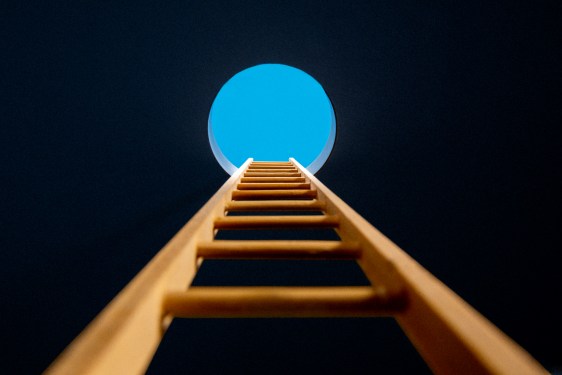 Point of view, looking up ladder sticking through hole in ceiling revealing blue sky