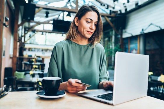 Young woman shopping online in cafe using laptop and credit card