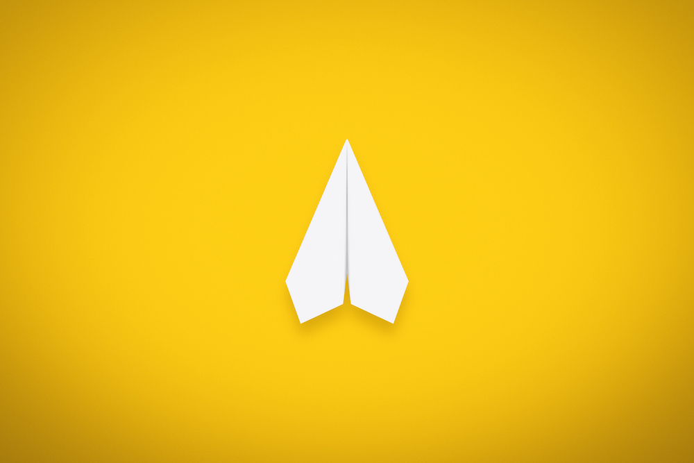 A Single Paper Airplane on Yellow Background