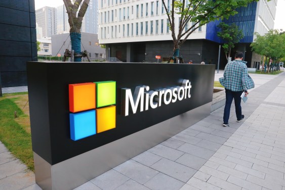 A man walks past a logo of Microsoft outside an office building at Shanghai Caohejing Hi-Tech Park