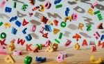 Conceptual image of colourful falling letters, casting shadows on a white wall.