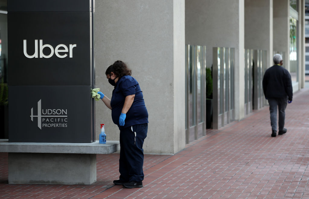 SAN FRANCISCO, CALIFORNIA - MAY 18: A worker cleans a sign in front of the Uber headquarters on May 18, 2020 in San Francisco, California. Uber announced plans to cut 3,000 jobs and shutter or consolidate 40 offices around the world due to severely declining business as the coronavirus (COVID-19) pandemic continues. The cuts come two weeks after Uber cut 3,700 employees. (Photo by Justin Sullivan/Getty Images)