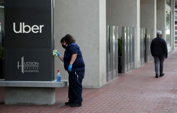 SAN FRANCISCO, CALIFORNIA - MAY 18: A worker cleans a sign in front of the Uber headquarters on May 18, 2020 in San Francisco, California. Uber announced plans to cut 3,000 jobs and shutter or consolidate 40 offices around the world due to severely declining business as the coronavirus (COVID-19) pandemic continues. The cuts come two weeks after Uber cut 3,700 employees. (Photo by Justin Sullivan/Getty Images)