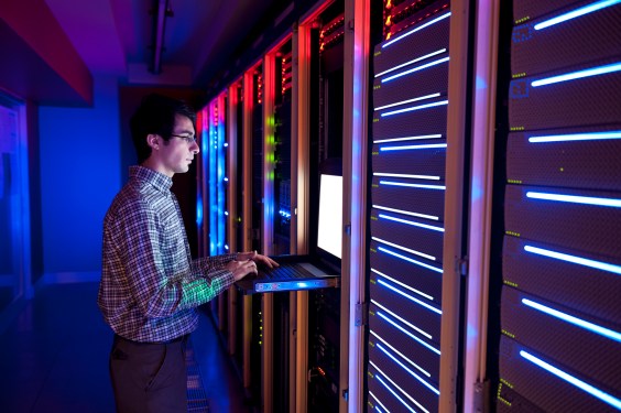 Modern interior of server room in datacenter. IT Engineer in Action Configuring Servers