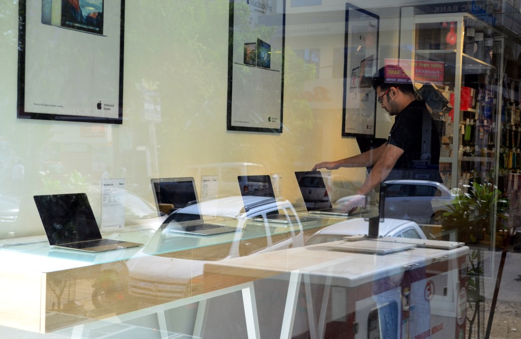 An indian salesman checks Apple Macbook laptops in an authorised Apple Store, in Allahabad on May 23,2016.An indian man works on his Apple macbook in his shop, in Allahabad on May 23,2016. Apple has announced that it will set up an app design and development center in southern India, shortly after company chief Tim Cook arrived in the country on his first visit. (Photo by Ritesh Shukla/NurPhoto via Getty Images)