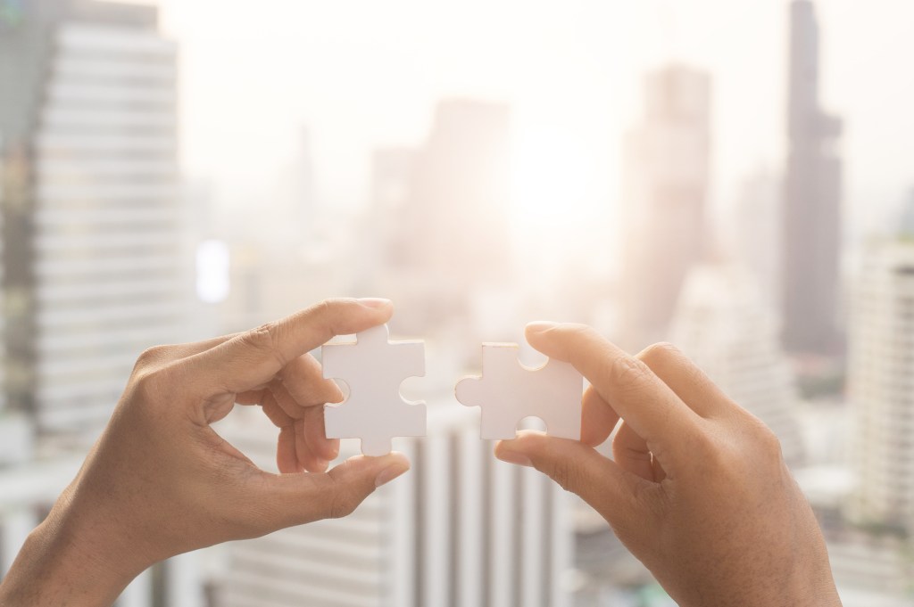 Closeup hand of woman connecting jigsaw puzzle with sunlight effect