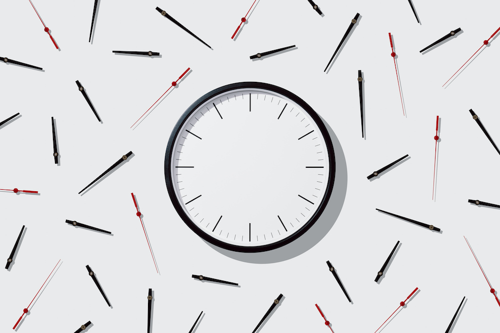 Blank Clock Face with Separated Hands on Solid Beige Colored Background Directly Above View.