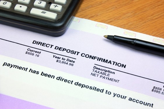 A direct deposit confirmation notice on a desk with a calculator and a pen.
