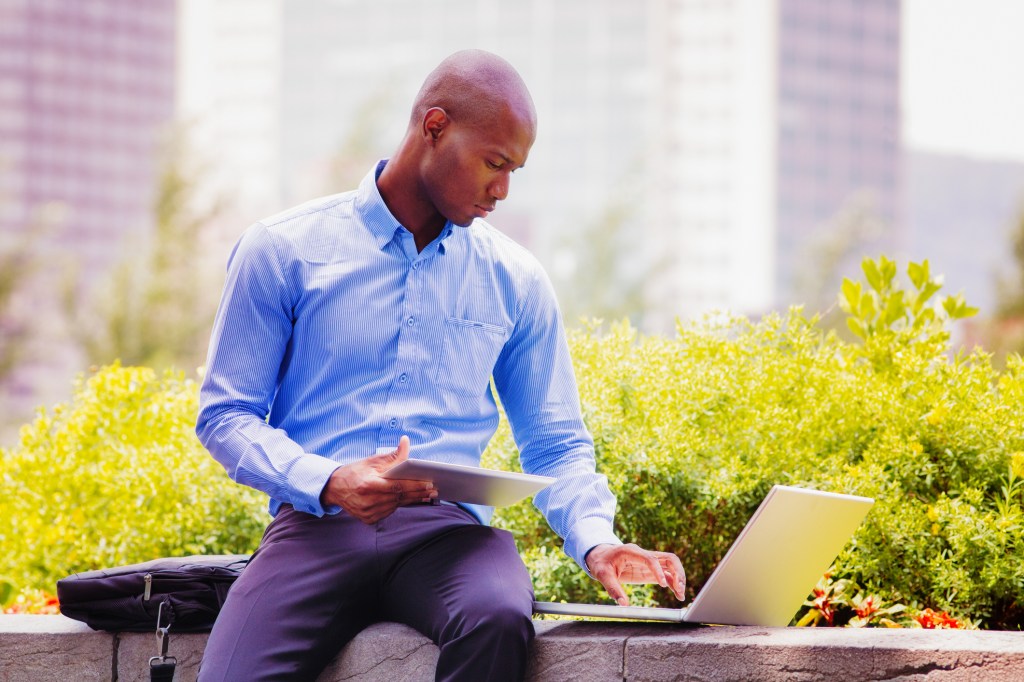 Salesman working outdoors with laptop and tablet. Photographed in Old Montreal.