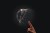 Cropped Image Of Hand Bursting A Bubble Against Black Backbround