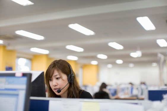 Woman talking with headset in front PC in office