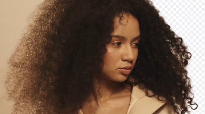 A woman with lots of curly hair, and the background has been carefully but automatically erased.
