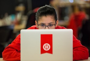 Young person working at a laptop with a Twilio logo on the back.
