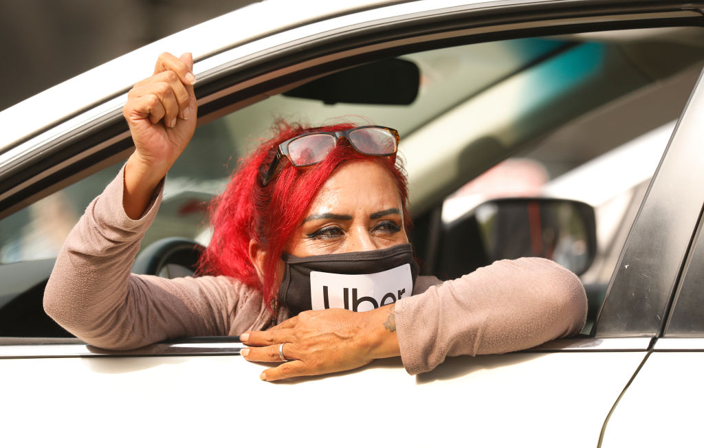 Rideshare driver Teresa Mercado raises her fist in support as app based gig workers held a driving demonstration with 60-70 vehicles blocking Spring Street in front of Los Angeles City Hall urging voters to vote no on Proposition 22.