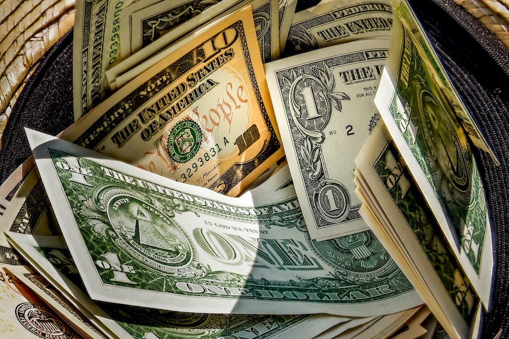 straw hat with a stack of dollar bills inside, donated to a successful beggar