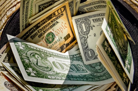 straw hat with a stack of dollar bills inside, donated to a successful beggar