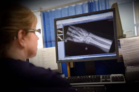A photo of clinical staff at a hospital looking at a patient's medical records on the computer screen.