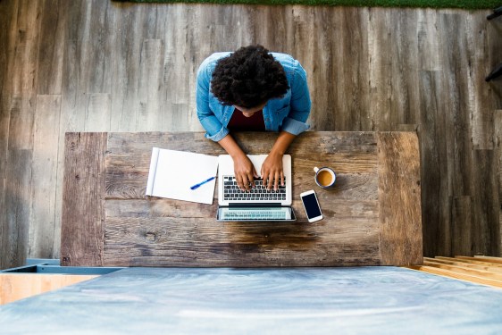 Overhead view of a woman using a computer whilst working/ studying in a modern looking room.