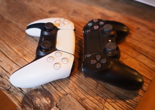 A Playstation 5 and 4 controller next to each other.