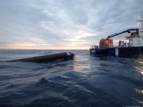 An Electron launch vehicle booster stage is recovered from the ocean by a ship.