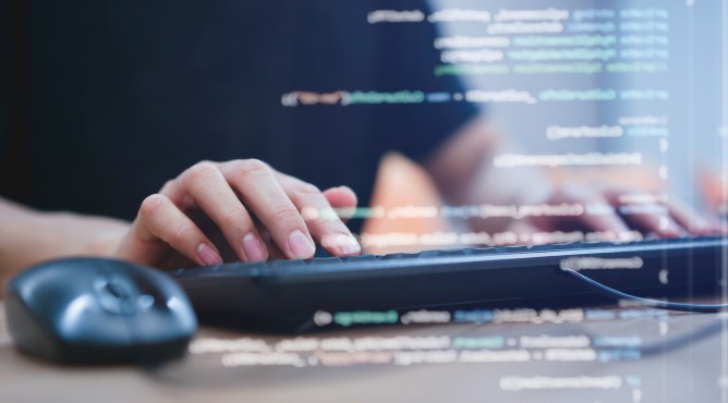 close up programmer student man hand typing on keyboard at computer desktop to input code language into software for study bug and defect of system in classroom , development of technology concept