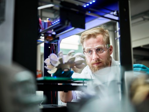 Technician looking at turbine wheel being printed in 3d printer