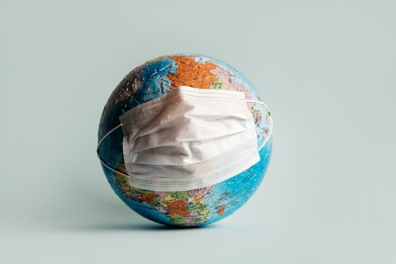 Globe made of jigsaw puzzles with a protective medical mask as a prophylaxis in the fight against coronavirus infection. Measures against the spread of the virus