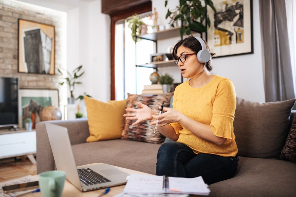Woman with headphones on working in a video conference from home.