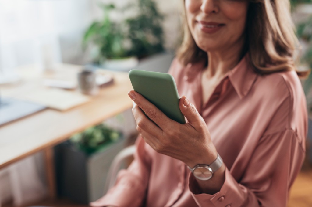 Woman in a pink shirt using her mobile phone while working from home
