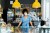 Young female owner wearing mask standing at counter in coffee shop