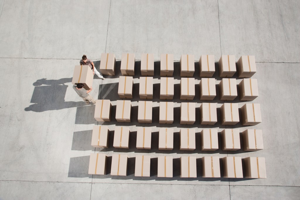 Delivery person adding box to a space to complete a square of delivery boxes.