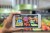 Woman holding a mobile phone using an augmented reality application to check special sale prices of fruits in a grocery. (Woman holding a mobile phone using an augmented reality application to check special sale prices of fruits in a grocery., ASCII,