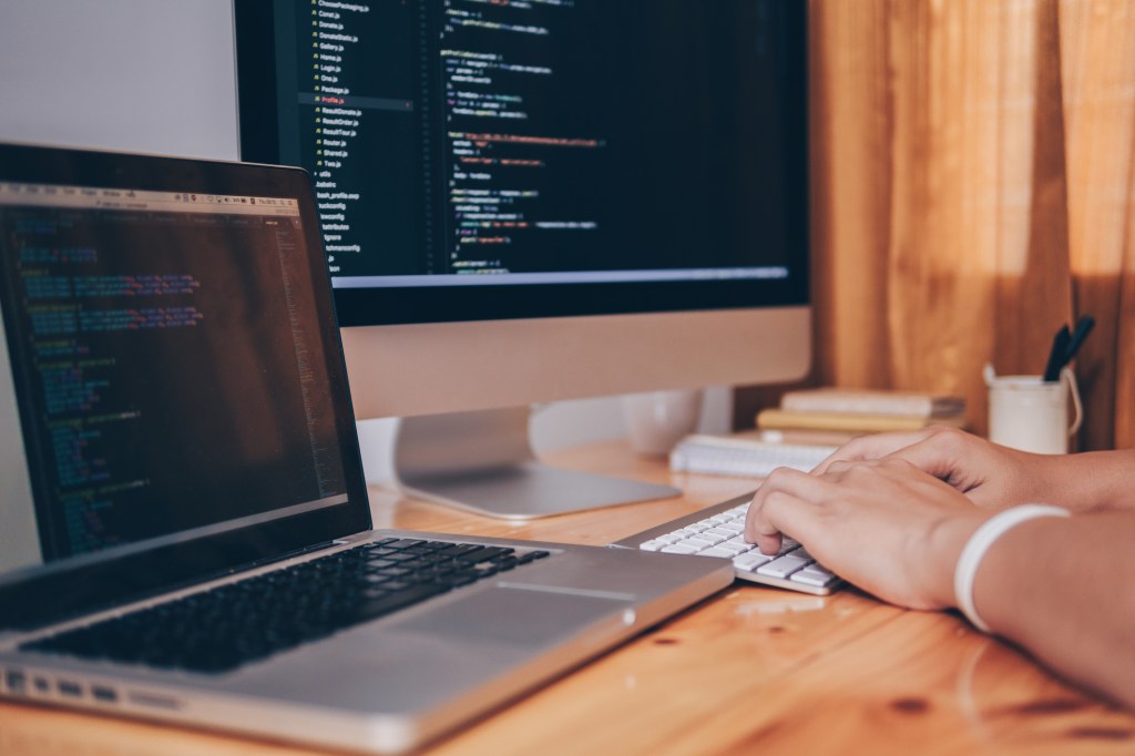 Cropped Image Of Computer Programmer Tying On Keyboard At Desk In Office