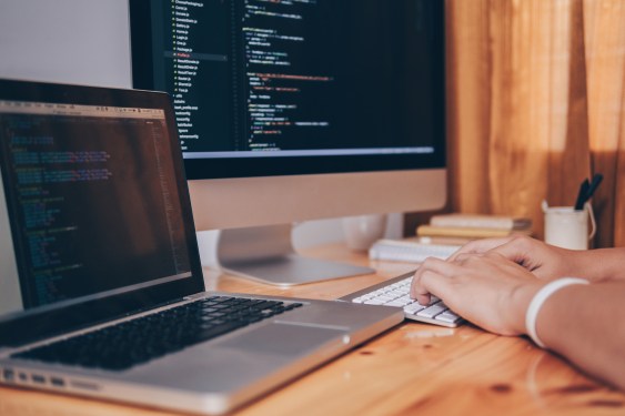 Cropped Image Of Computer Programmer Tying On Keyboard At Desk In Office