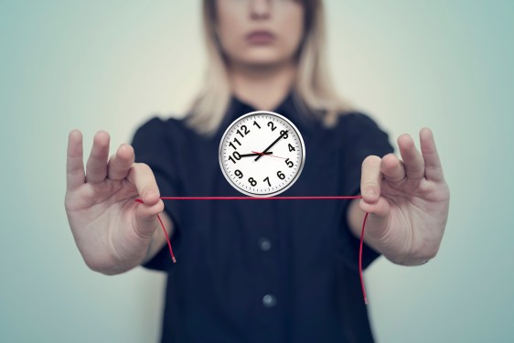 Woman's hands hold a wall clock balanced on a thread