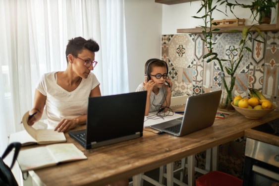 Boy uses laptop while his mother works from home