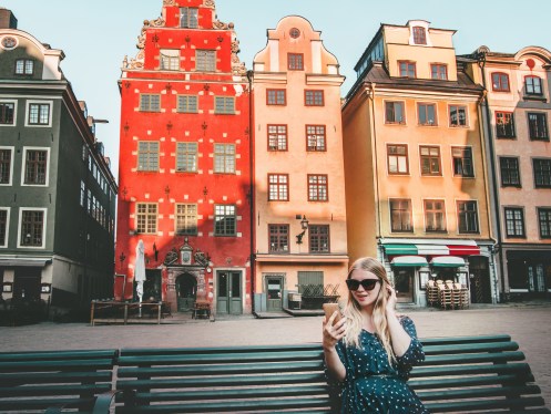 Woman tourist in Stockholm city Gamla Stan traveling lifestyle girl using smartphone blogging Europe trip vacations