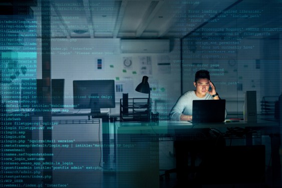 Developer coding alone in an office at night with code overlaying the picture.