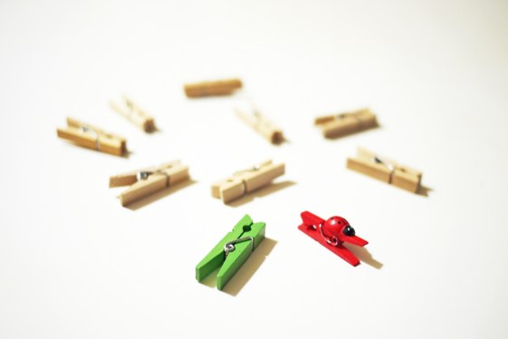 Scattered clothes pegs with red and green ones pushing forward
