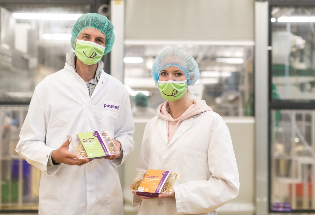 Two technicians in a lab holding Planted brand meat alternative packages.