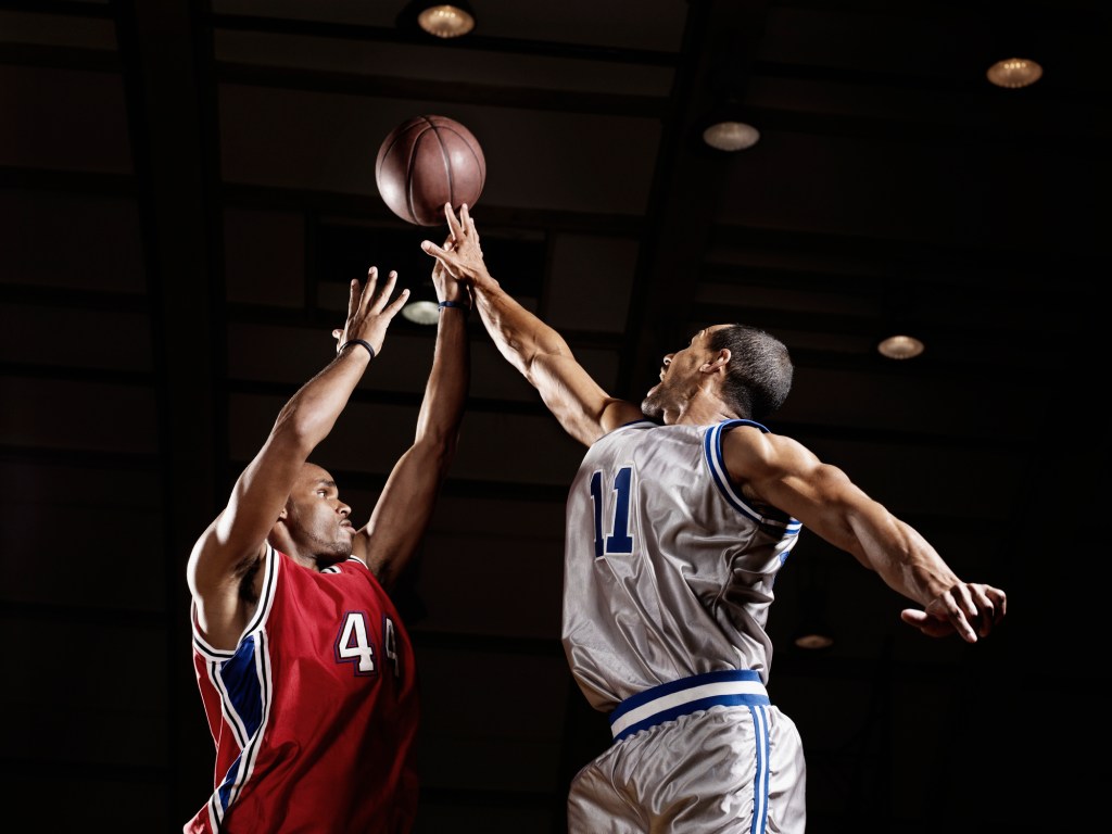 Basketball player trying to take basketball from opponent