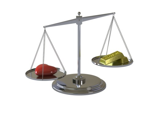 Image of a scale with a heart on one side and gold bars on the other.