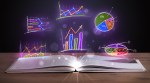 Book on wooden deck with glowing graph illustrations and symbols